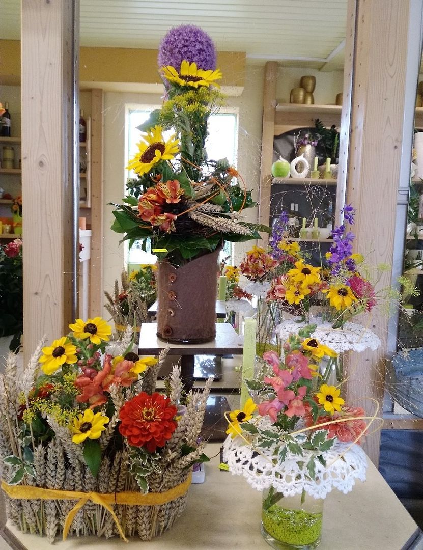 Florale Topfdekoration mit Sonnenblumen, Margeriten und bunten Blüten in einem Geschäft