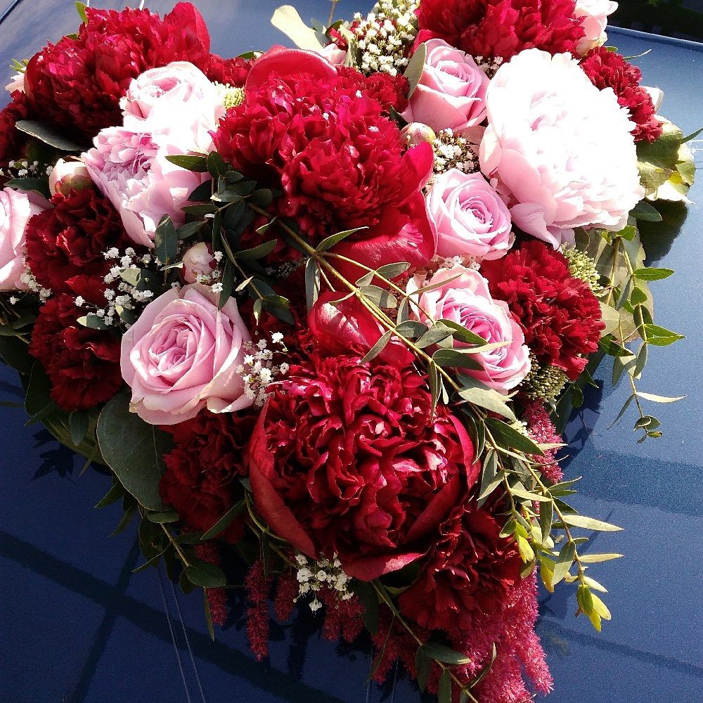 Dicht gebundene Blumen aus roten Pfingstrosen und rosa Rosen mit dekorativem Grün
